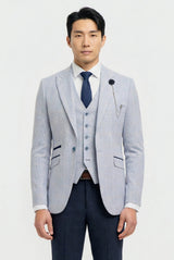 Man wearing a light gray blazer, navy vest, and dark blue tie on a white background